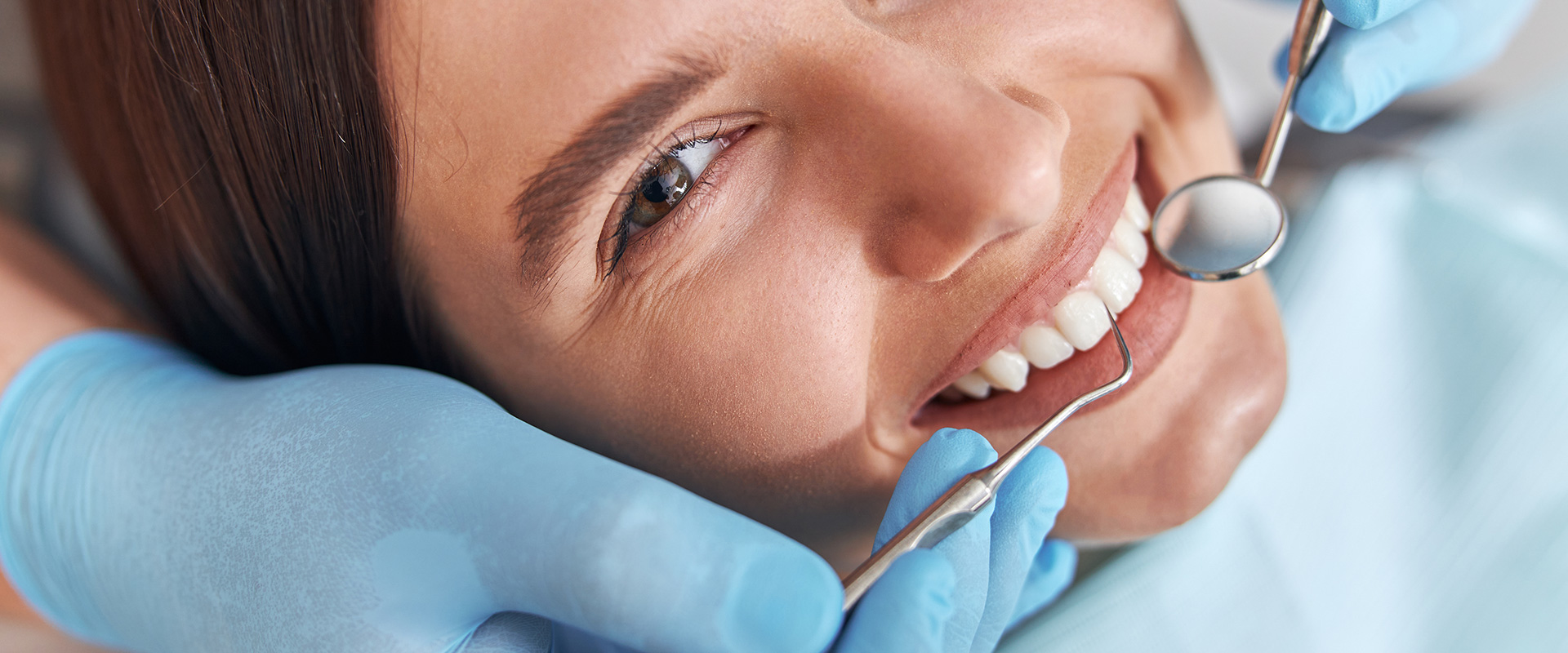 Hymyilevä hammashoitopotilas tutkittavana hammaslääkärin hoitotuolissa. Hammaslääkäri Helsinki.